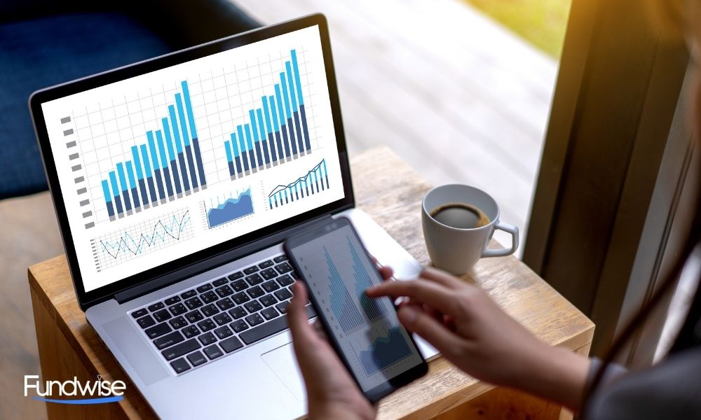 business man looking at his cellphone and laptop with business analytics